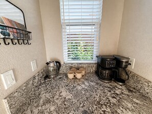 A kitchen with a coffee maker, a kettle, and a window with blinds. - Mystery Run Retreat | Pool, Spa, Billiards & BBQ (Chico)