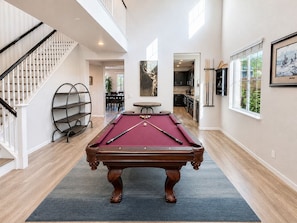 A pool table in a spacious room with a staircase and a dining area in the background. - Mystery Run Retreat | Pool, Spa, Billiards & BBQ (Chico)