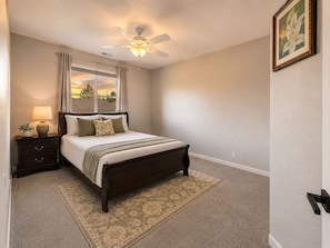 A bedroom with a bed, nightstand, lamp, and a ceiling fan. - Mystery Run Retreat | Pool, Spa, Billiards & BBQ (Chico)