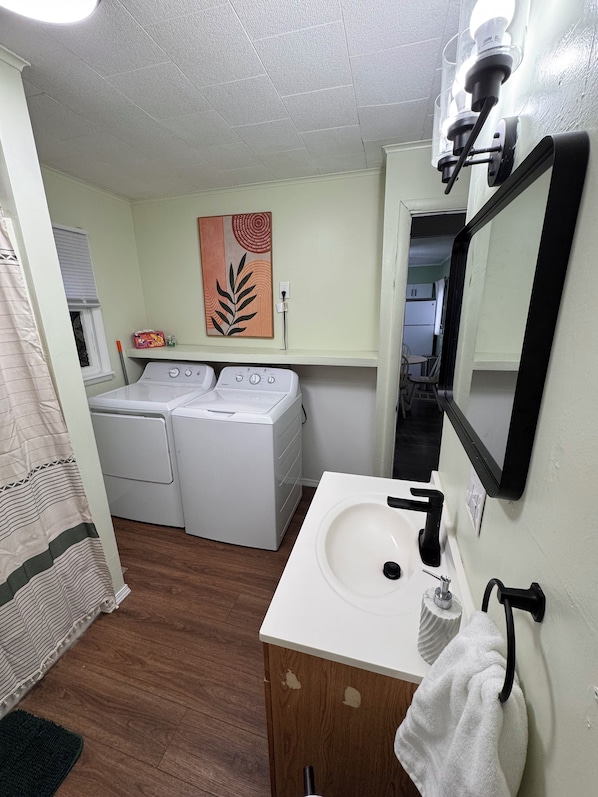 A laundry area with two washing machines, a sink with a mirror, and a towel rack.