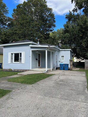 A single-story house with a front porch, a visible door, and a chimney.