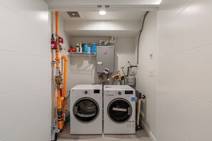 Uma lavanderia com duas máquinas de lavar de carregamento frontal, uma válvula de controle e um aquecedor de água.