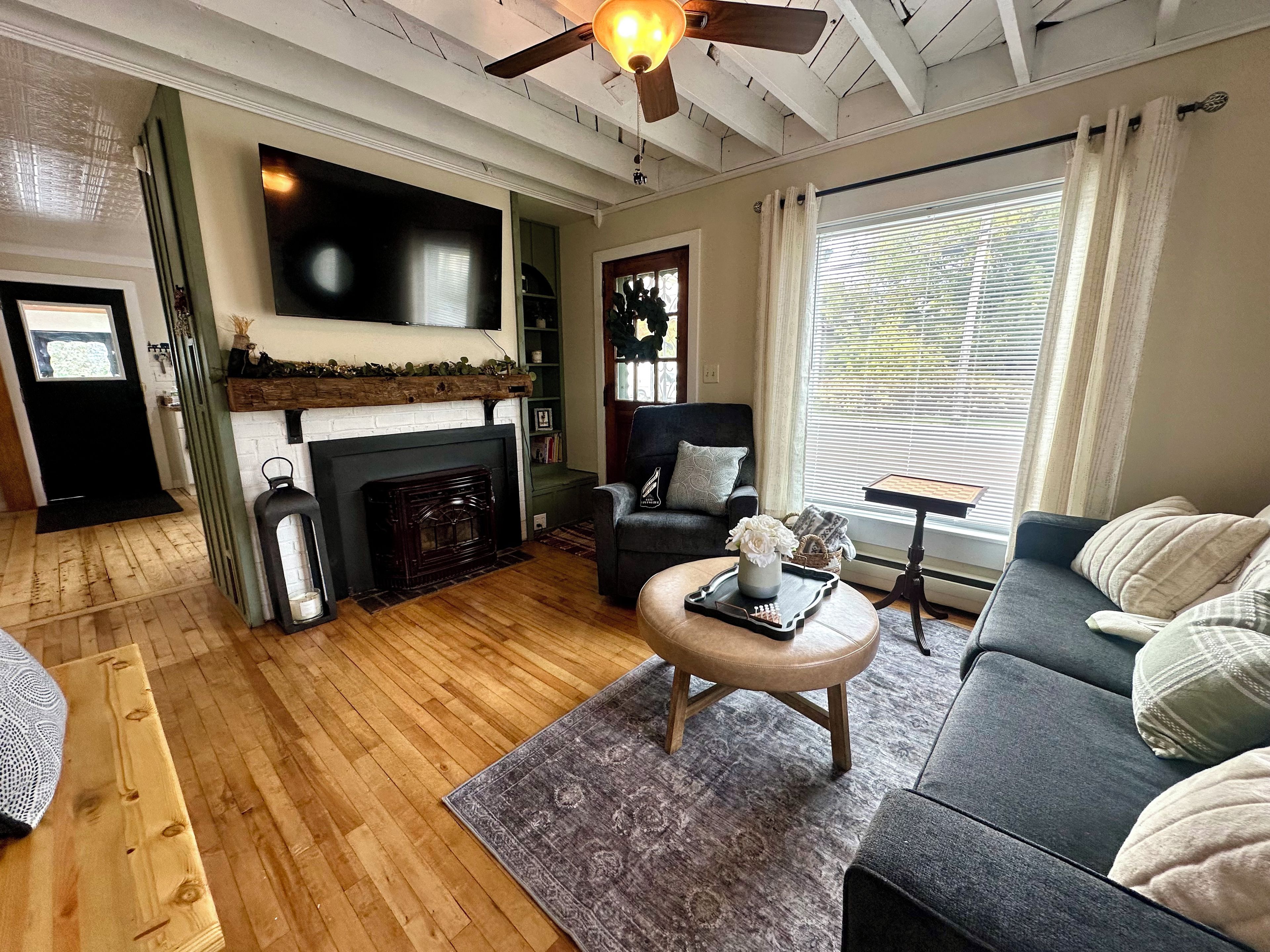 Una sala de estar con chimenea, un sofá, una mesa de centro y un televisor montado en la pared.