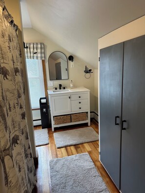 A bathroom with a white vanity, a mirror, a towel rack, and a grey wardrobe. - Rev and Ride Trailside Retreat: Direct ATV & Snowmobile Access: Sleeps 9 (Colebrook)