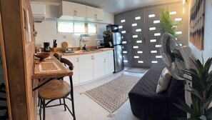 A modern kitchen with a dining area, including a wooden table and chairs, a refrigerator, and a microwave. - EncantoPlayeroPR is the choice you should make to stay comfortable (Playa Fortuna)