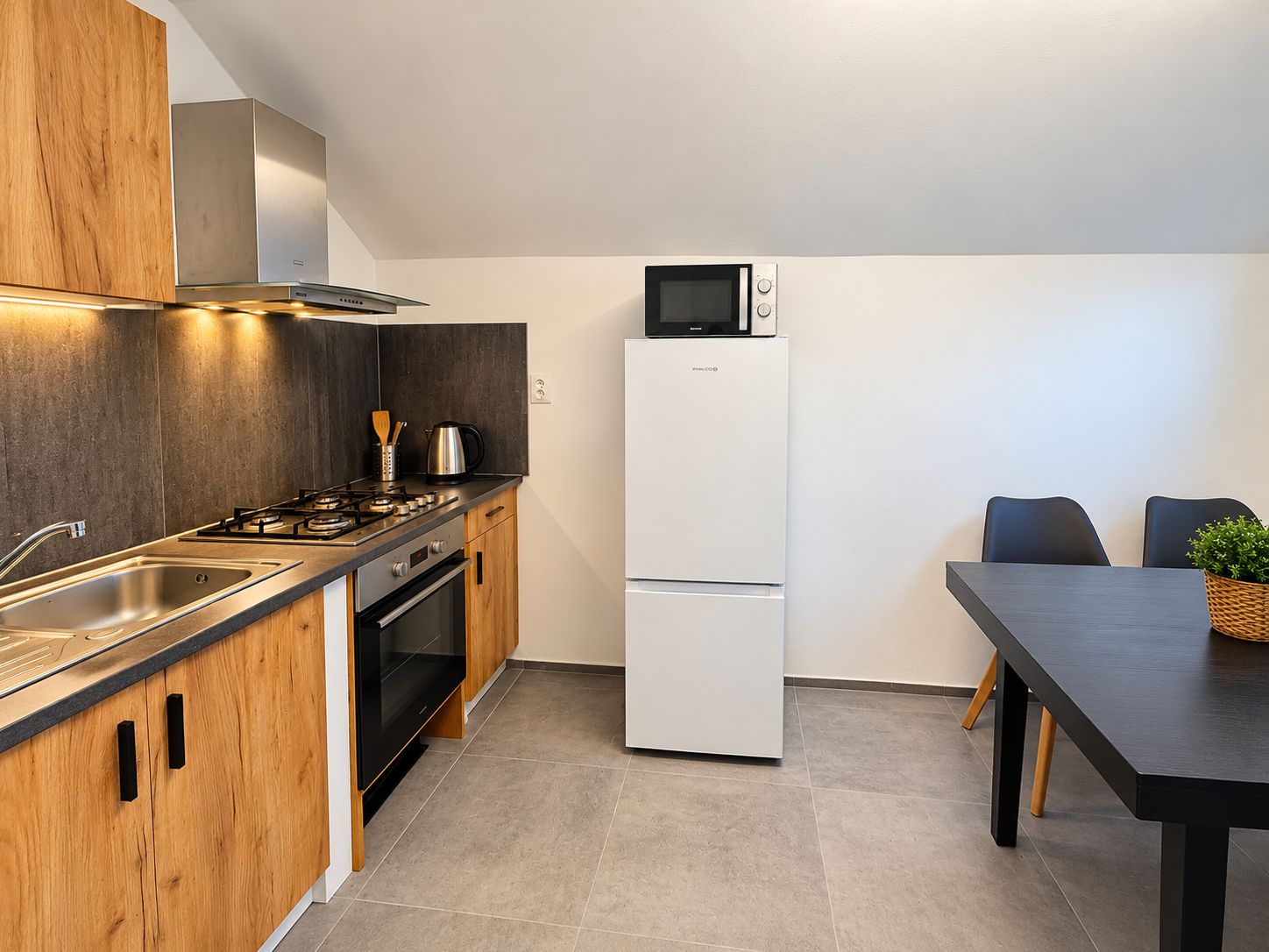 Een moderne keuken met een gasfornuis, oven, magnetron en een koelkast met dubbele deuren.