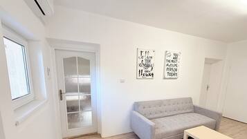 Un salon minimaliste avec un canapé gris, une petite table en bois et deux œuvres d’art murales inspirantes.