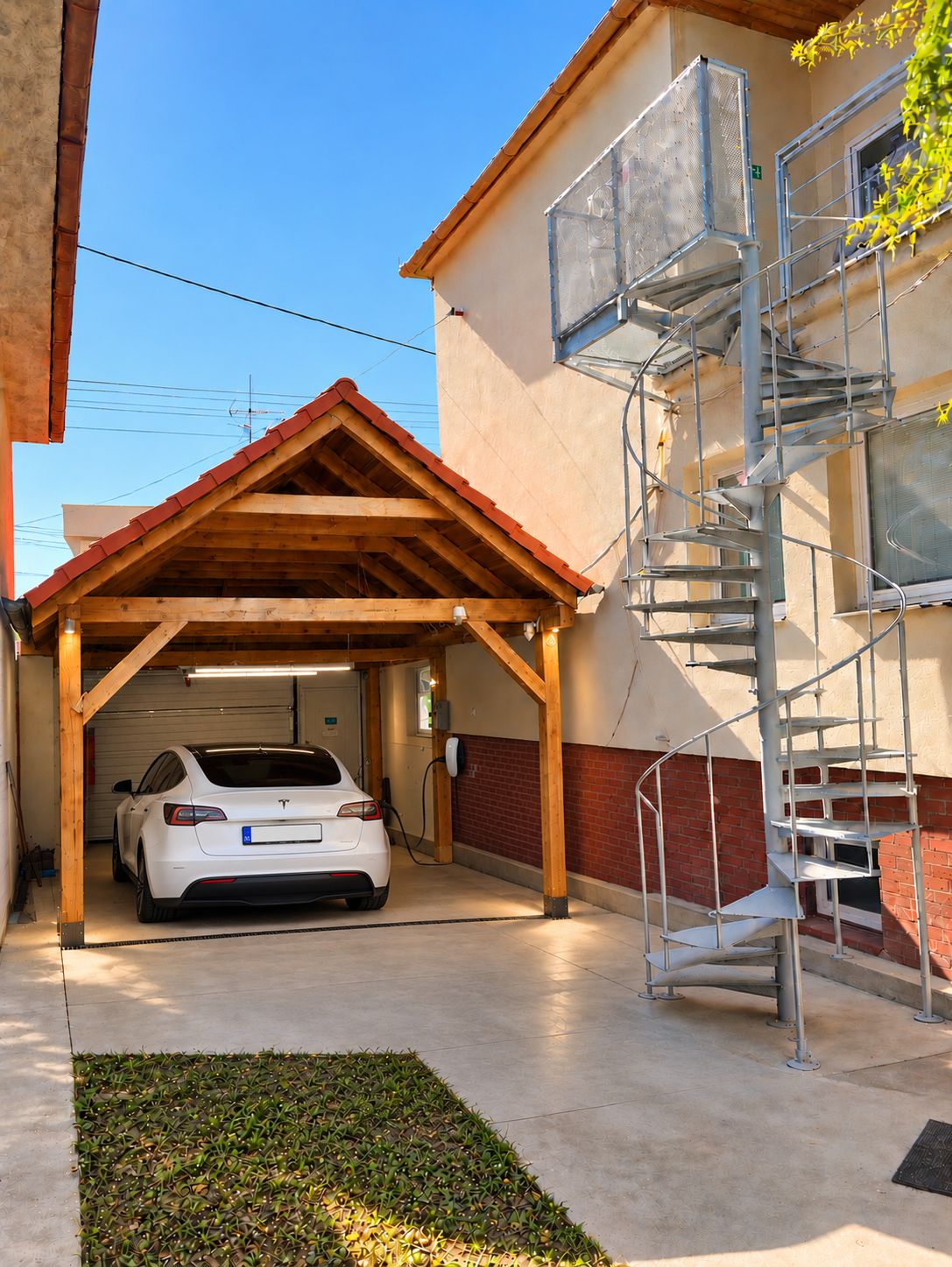 Ein weißes Auto steht in einer Garage mit Holzboden und einem metallenen Wendeltreppe rechts.