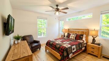 A bedroom with a bed, a chair, a desk, and a ceiling fan.