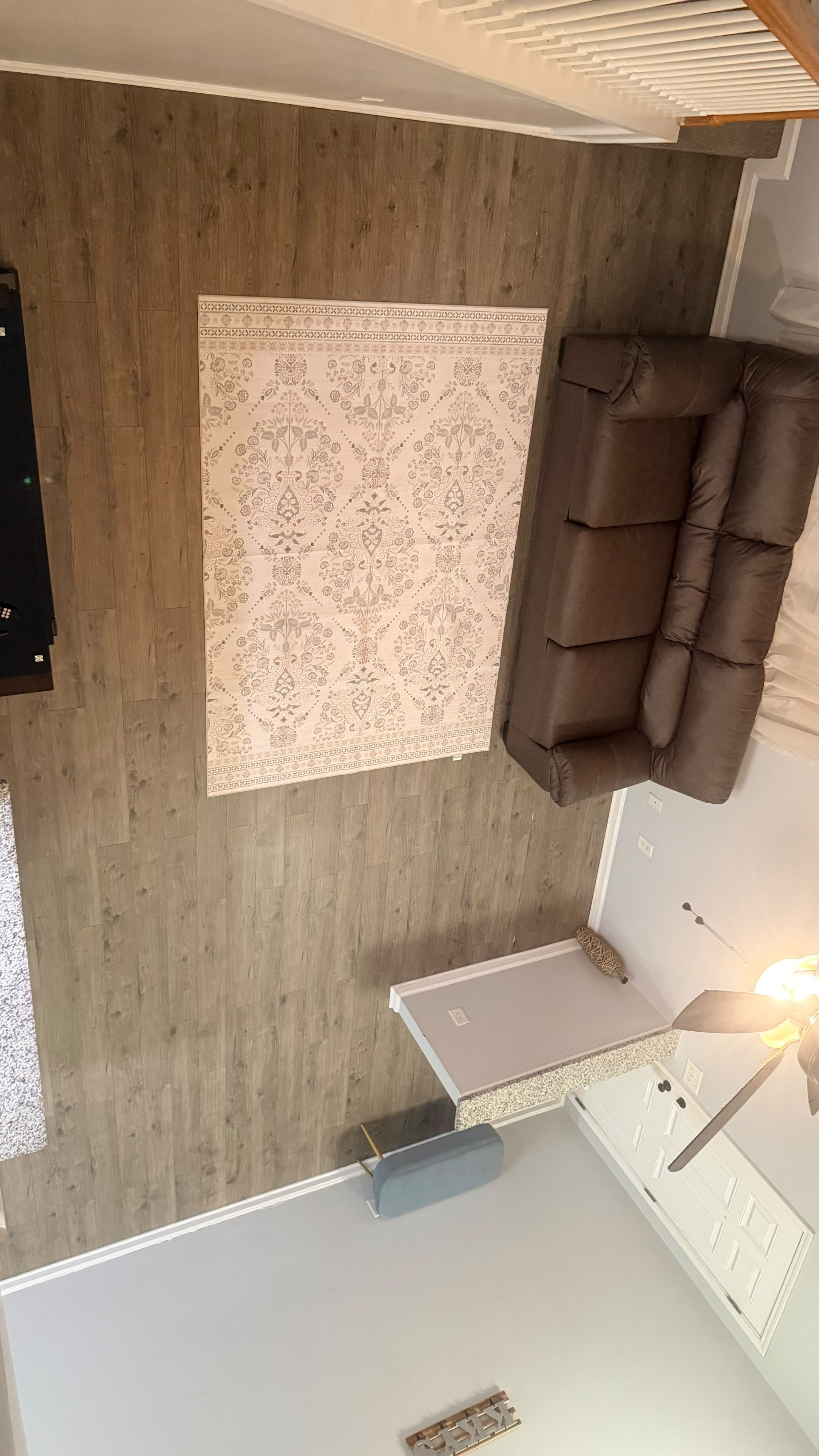 A room with a brown leather sofa, a patterned rug, and a small table.