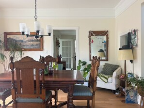 Un coin repas avec une table et des chaises en bois, un lustre et un miroir au mur.