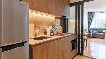 A modern kitchen with a stainless steel refrigerator, wooden cabinets, a double sink, and a coffee machine.