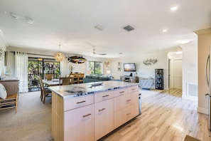 A spacious living area with a large kitchen island, dining area, and a television. - Blind Pass Condos at Bowman's Beach A205 on beautiful Sanibel Island (Sanibel)