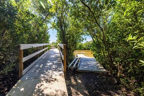 A wooden boardwalk leading through a dense, green forest. - Blind Pass Condos at Bowman's Beach A205 on beautiful Sanibel Island (Sanibel)