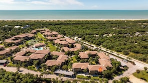 Un barrio residencial con varias casas, una piscina y una playa al fondo.