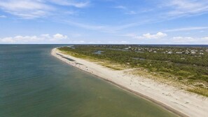 A coastal landscape with a sandy beach, a clear sky, and a distant view of a residential area. - Blind Pass Condos at Bowman's Beach A205 on beautiful Sanibel Island (Sanibel)