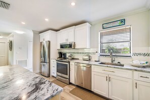 A kitchen with white cabinets, stainless steel appliances, a marble countertop, and a sign above the window. - Blind Pass Condos at Bowman's Beach A205 on beautiful Sanibel Island (Sanibel)