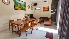Un comedor con mesa y sillas de madera, un sofá y un televisor.