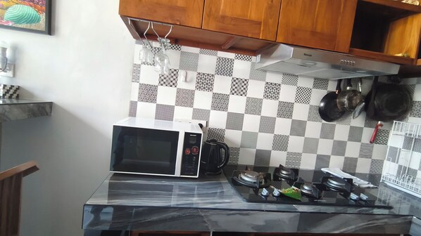 Una cocina con microondas, estufa a gas y un salpicadero a cuadros.