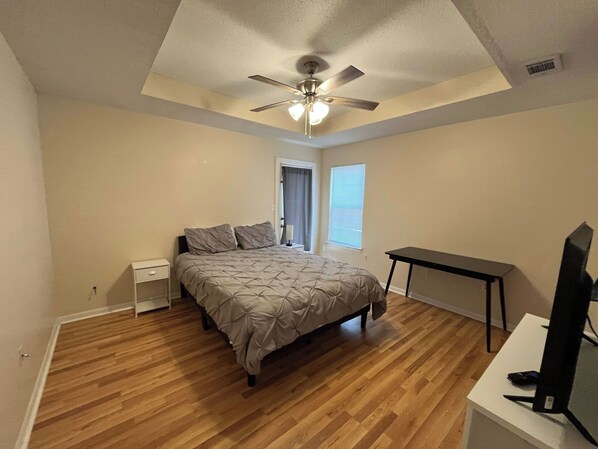 A bedroom with a bed, a desk, a ceiling fan, and a window. - Spacious Home sleeps 10 in quiet Neighborhood (Fort Walton Beach)