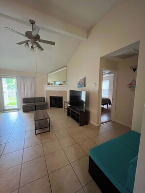 Una sala de estar con ventilador de techo, televisor, sofá y mesa de centro.