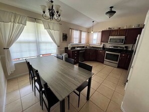 A kitchen with a dining table, chairs, cabinets, and appliances. - Spacious Home sleeps 10 in quiet Neighborhood (Fort Walton Beach)