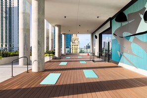 A modern building with a wooden deck, large columns, and a view of a historic tower in the distance. - High-Floor Studio| Rooftop Pool + Beach Club | Downtown Miami (Miami)