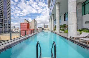 A swimming pool with steps leading into it, surrounded by modern buildings and a clear sky. - High-Floor Studio| Rooftop Pool + Beach Club | Downtown Miami (Miami)