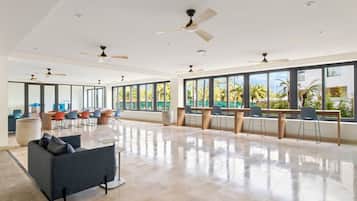 A spacious room with a large window, a ceiling fan, and a seating area with chairs and a sofa.
