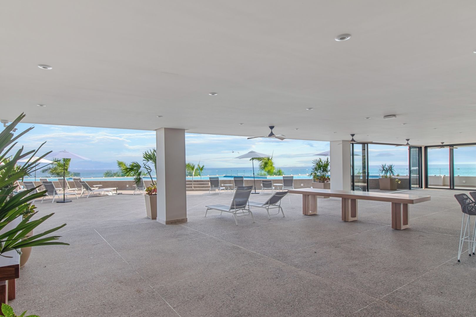 An outdoor terrace with a pool, lounge chairs, and a dining area with a table and chairs.