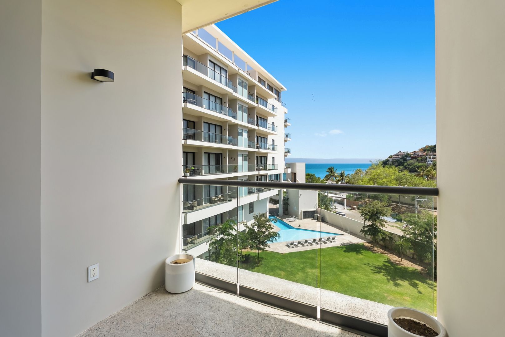 Un balcon donnant sur une piscine et un immeuble à plusieurs étages.