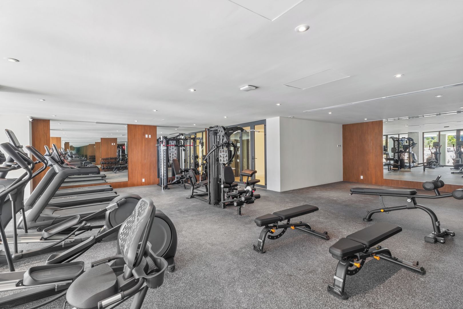 A gym with treadmills, weight machines, and benches.