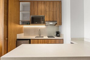 A modern kitchen with wooden cabinets, a microwave, a coffee maker, and a dishwasher.