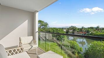A balcony with a view of a lake and surrounding greenery.
