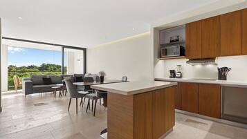 A modern kitchen with a dining area, wooden cabinets, and a view of greenery.