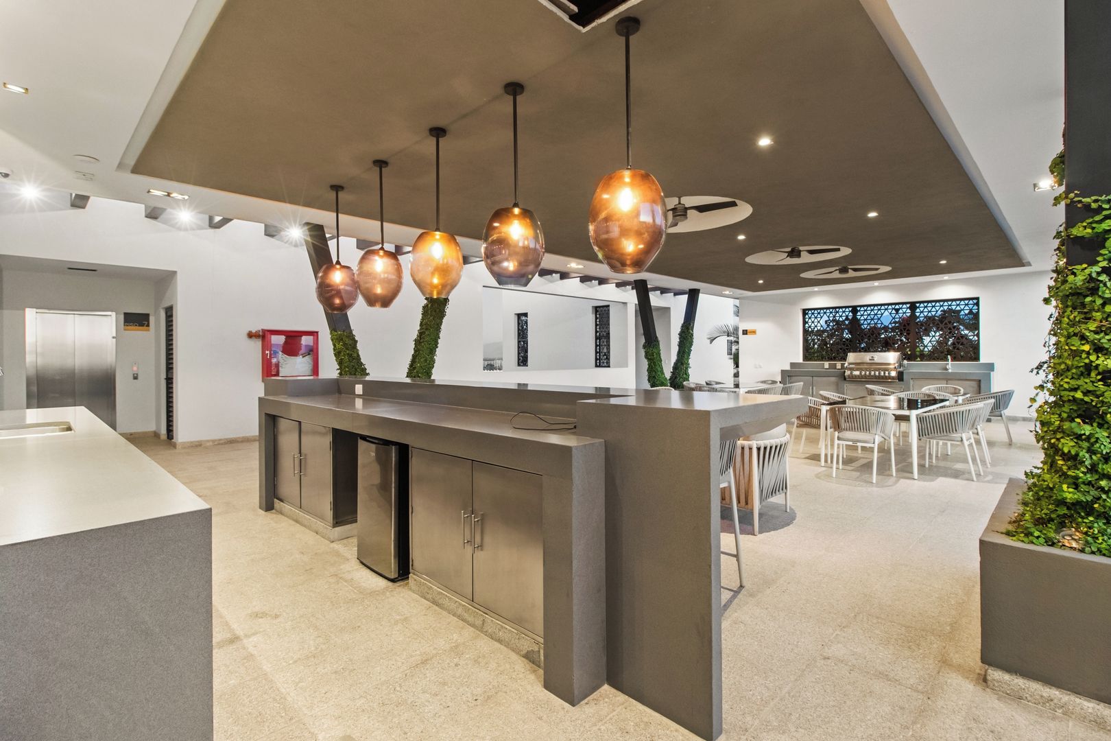 A modern kitchen with a central island, pendant lighting, and a dining area with chairs.