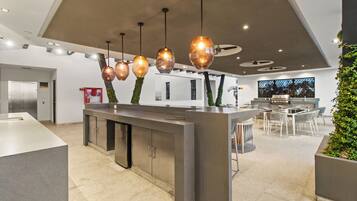 A modern kitchen with a central island, pendant lighting, and a dining area with chairs.