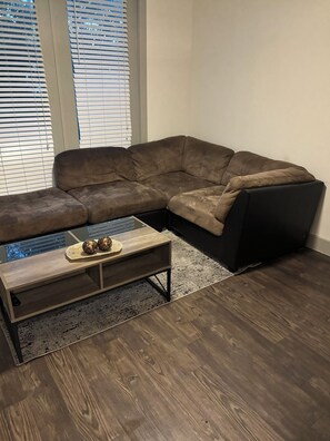 A living room with a sectional sofa, a coffee table, and a rug. - Enjoyable apartment in quaint Addison with fitness room access (Addison)