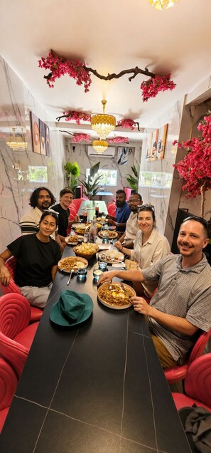 A dining area with a long table, multiple chairs, and a chandelier.