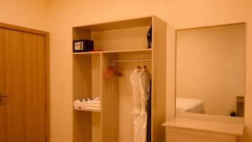 A hotel room with a wooden wardrobe, a mirror, and a bedside table.