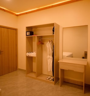 A hotel room with a wooden wardrobe, a mirror, and a bedside table.