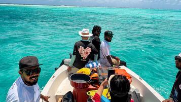 A group of people on a boat with turquoise water and a clear sky.