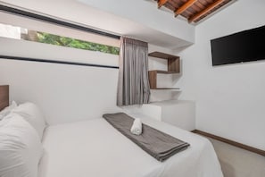 A modern bedroom with a bed, a window with curtains, a flat-screen TV, and built-in wooden shelves. - Walkable Provenza Apt Jacuzzi (Medellín)