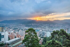 A cityscape with a sunset, buildings, and mountains in the background. - Premium Extended Stay Comfort Location (Medellín)