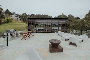 Eine Außenpatio-Terrasse mit Grill, Sitzgelegenheiten und einer Pergola.
