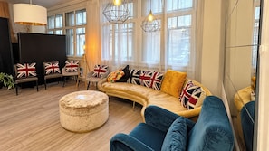 A living room with a curved sofa, ottoman, and chairs with British flags. - East London Studio, Sleeps 2 with WiFi (London)