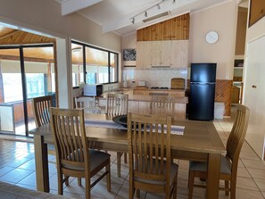 Une cuisine moderne avec des meubles en bois, un réfrigérateur noir et un coin repas comprenant des chaises et une table en bois.