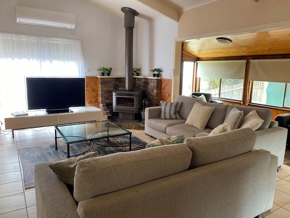 A living room with a sofa, a glass coffee table, a fireplace, and a television.