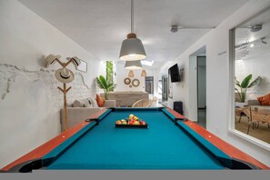 A pool table with balls, a sofa, and a television in a modern room with white walls and a ceiling fan. - Private House Provenza Big Jacuzzi (Medellín)