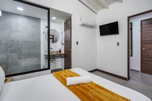 A modern hotel room with a large bed, a television mounted on the wall, and a separate bathroom area. - Private House Provenza Big Jacuzzi (Medellín)